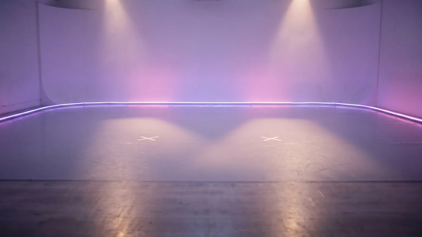 An empty lavender dance studio glowing with soft neon light, with two taped marks on the floor lit by two beams, waiting for two dancers